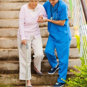 A nurse helping a patient walk down steps