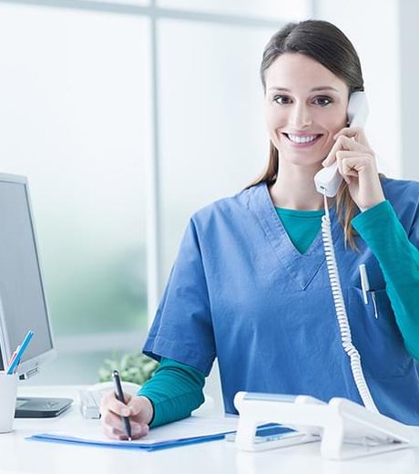 A smiling receptionist answering the phone at the front desk